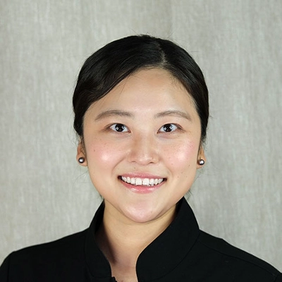 Dentist Deborah Chung Smiling In Front Of Grey Background